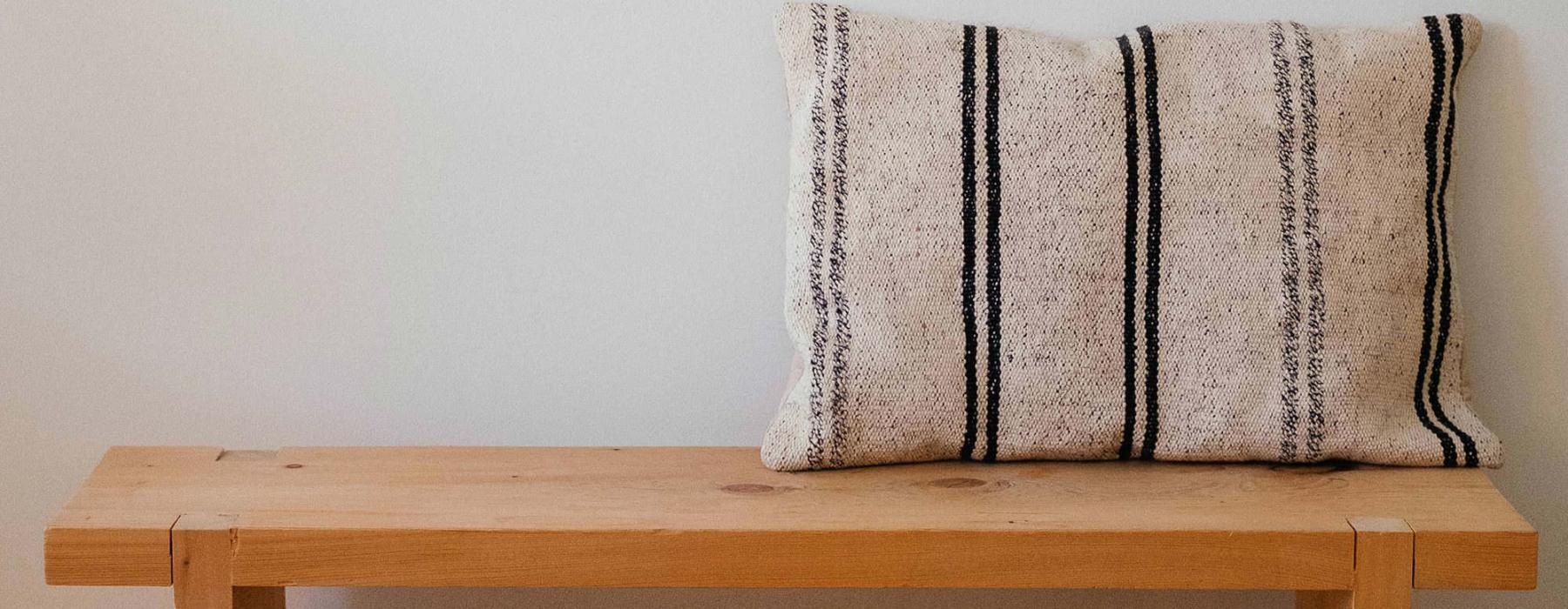 a wooden bench with a striped pillow on it