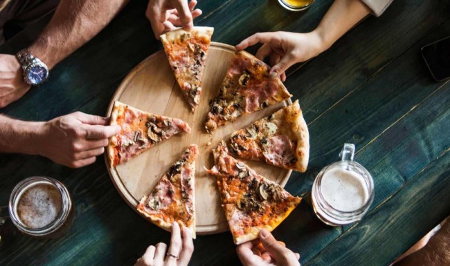 a group of people eating pizza