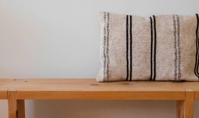 a wooden bench with a striped pillow on it