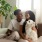 a young couple sit on couch with their dog