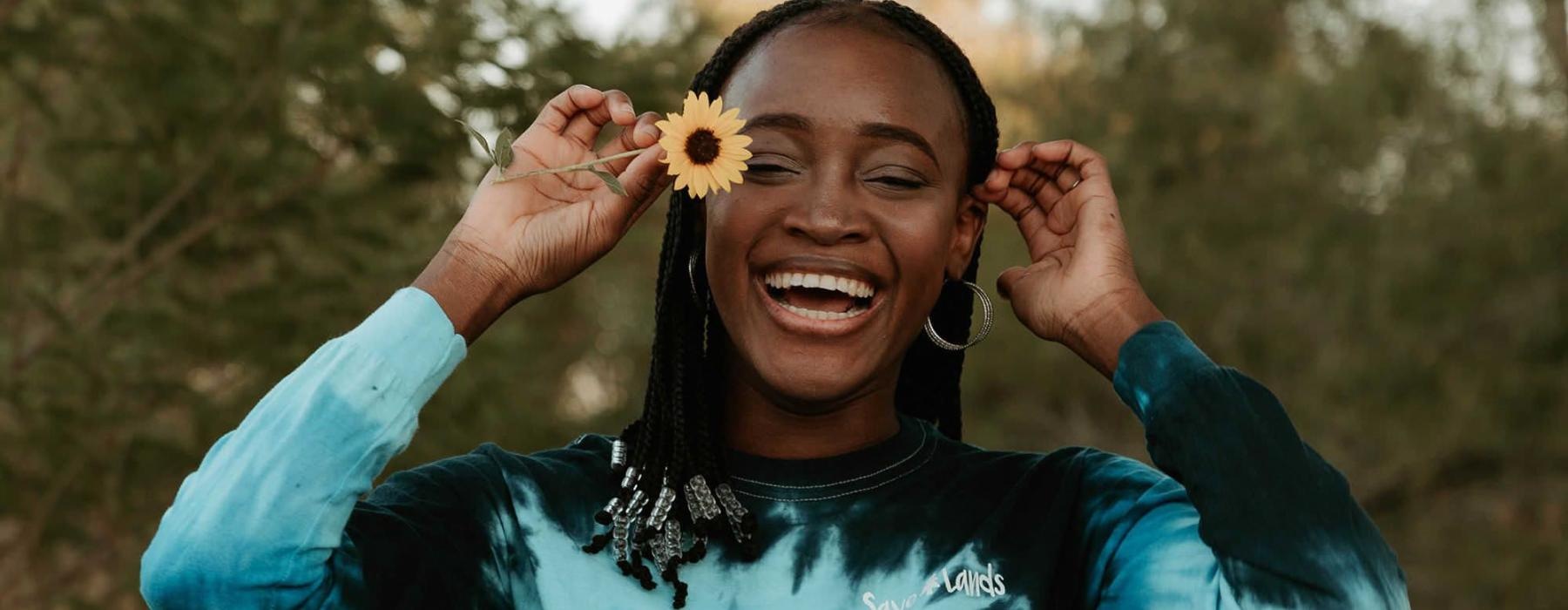 woman holds a flower in her hair in a park