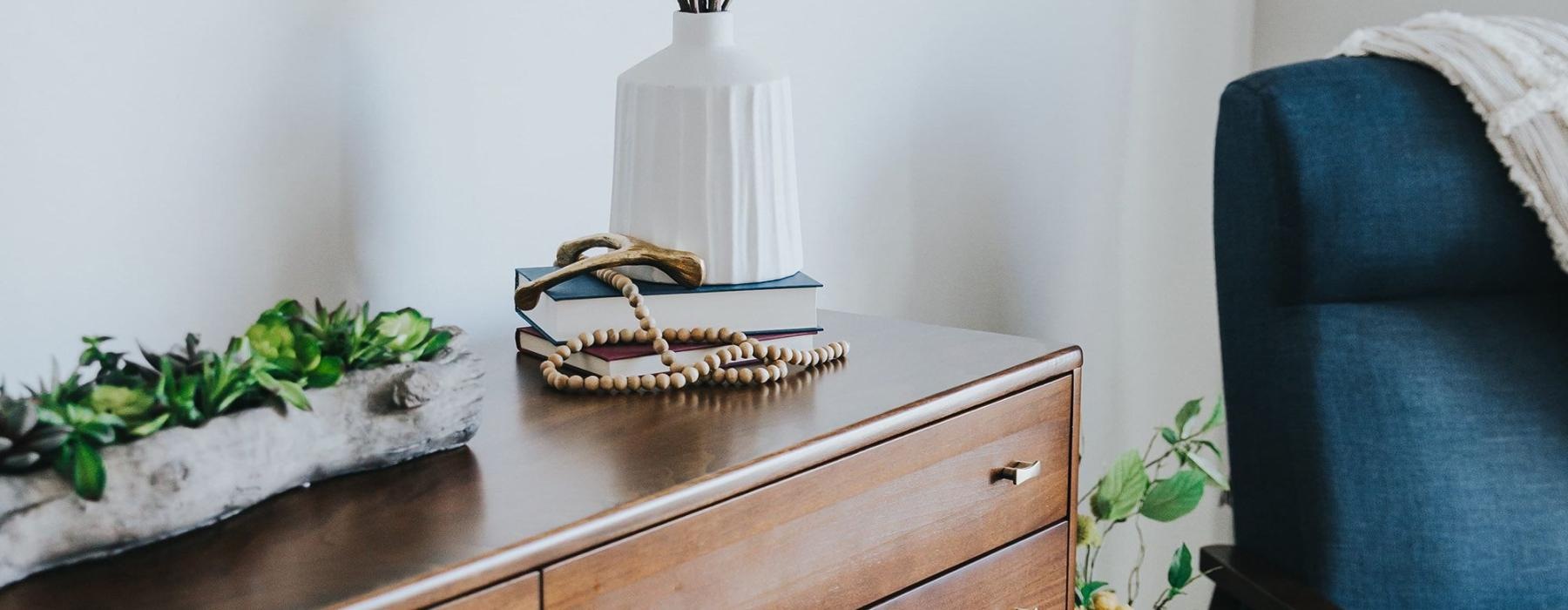 a dresser with a vase of plants on top
